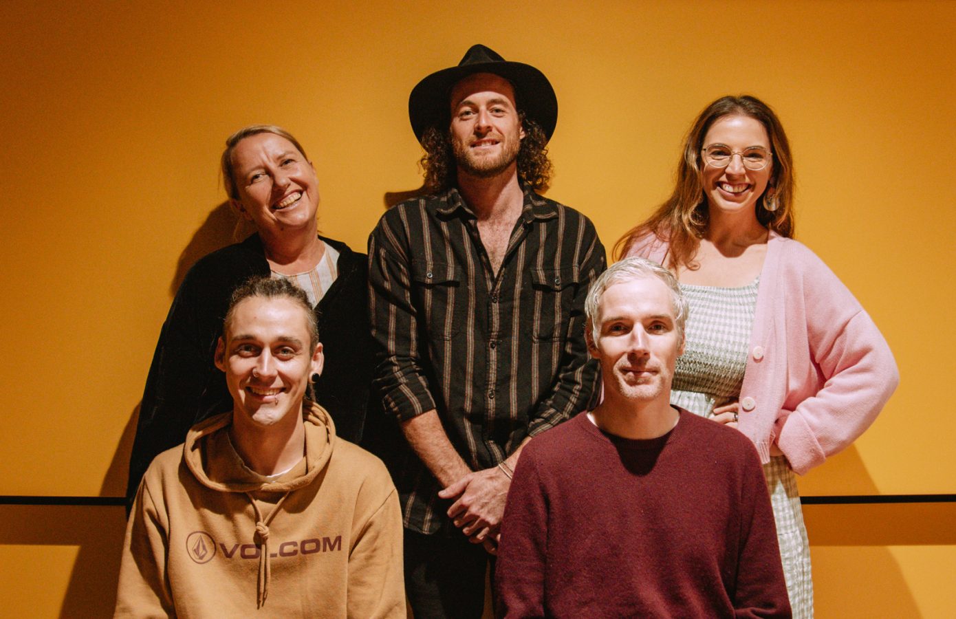 The five new 2023 regional MusicNSW team members photographed smiling with a yellow background.