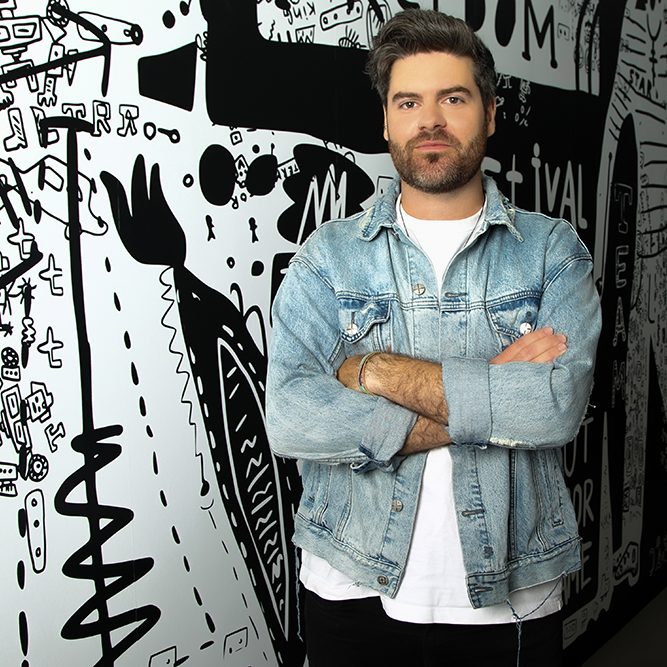 Jono Harrison Headshot SQUARE Isaac Harrison against black and white painted wall