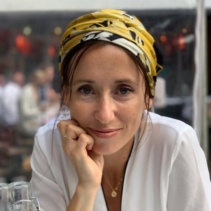 Marion Briand looking into camera with yellow patterned head scarf and white shirt
