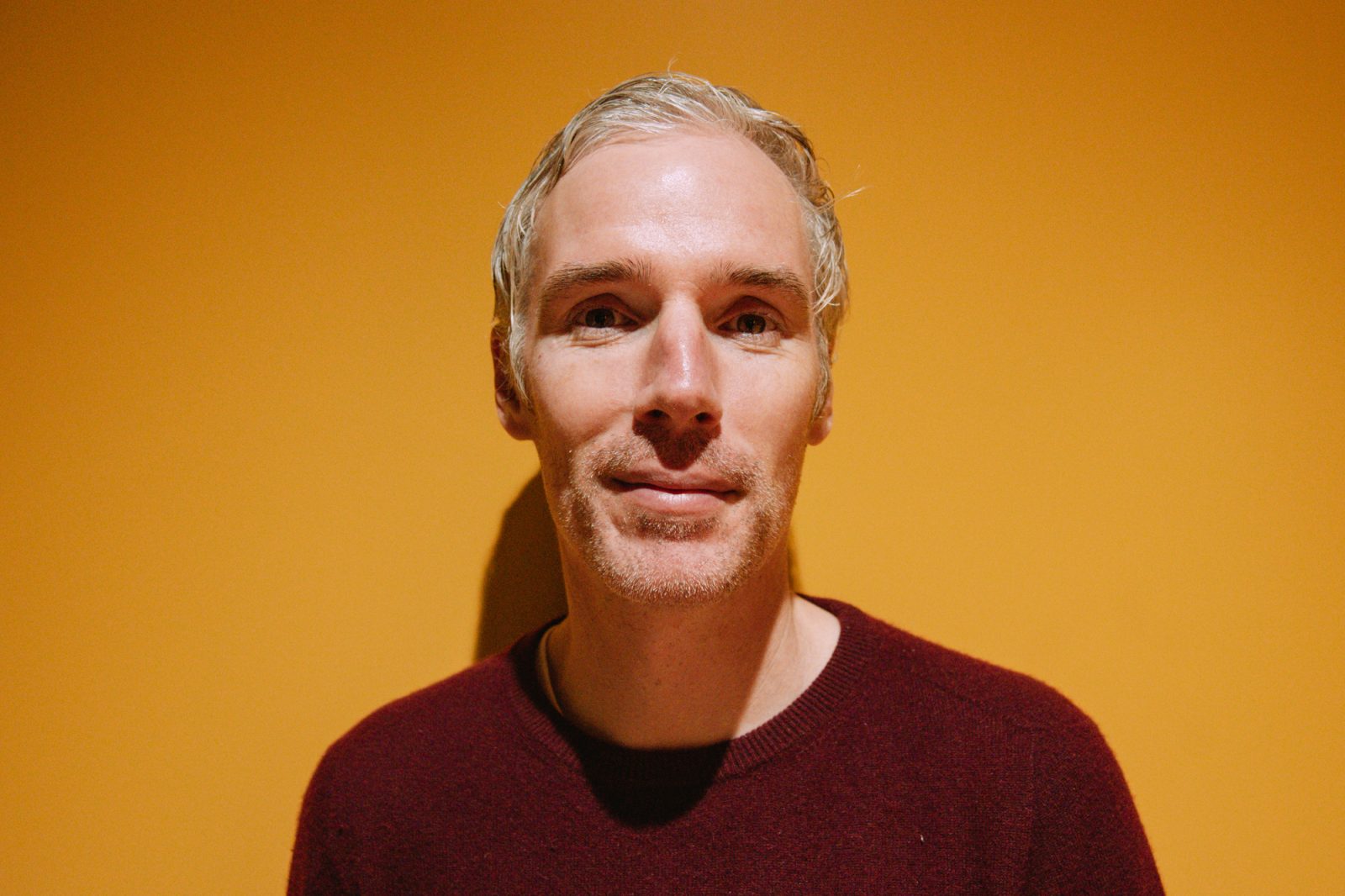 Regional Manager Dave Burgener Head and shoulder shot of Dave with short grey hair wearing a dark red crew jumper standing in front of a yellow background.