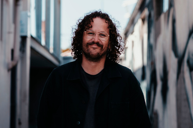 Joe Muller looking at the camera, standing against a city laneway background