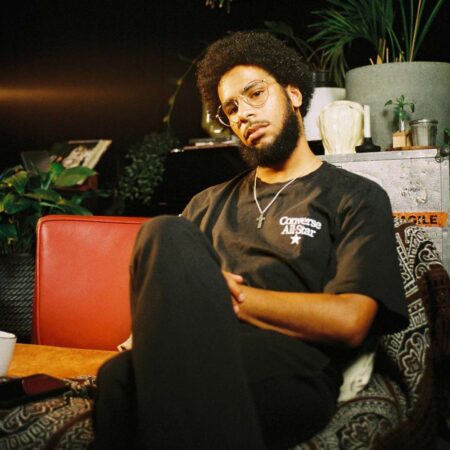 Ruu Ruu wearing a black shirt sitting on a couch