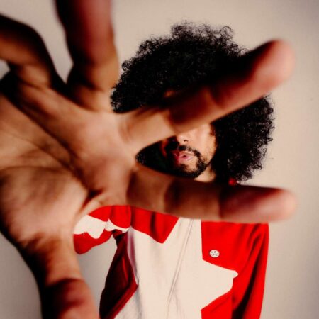 Zion Garcia Zion Garcia in a red and white top is reaching for the camera, obscuring his face