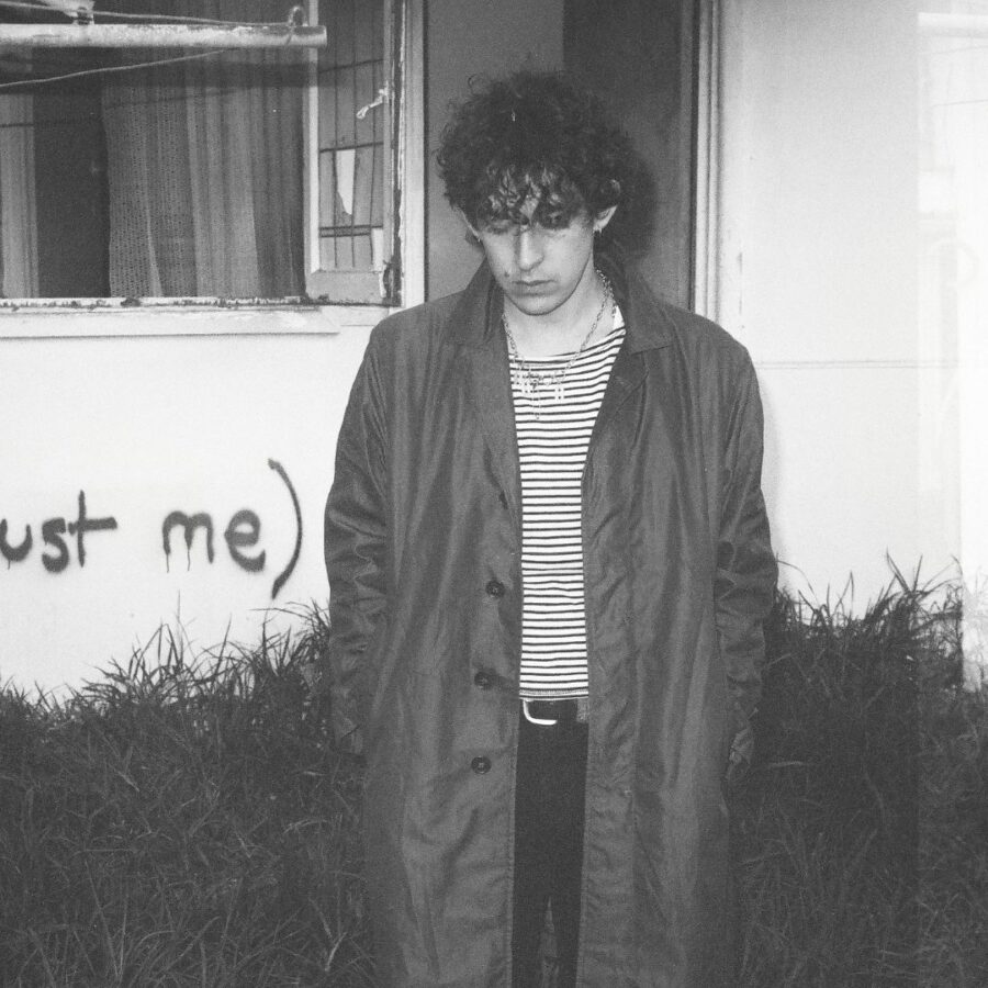 Olive Rush A black and white photo of Olive Rush standing in front of a house with the words trust me written on it